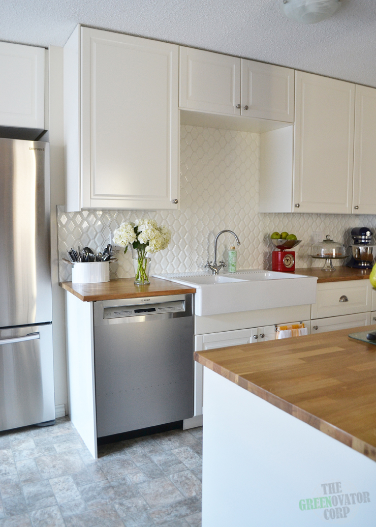 A bright white Ikea galley kitchen renovation with butcher block counters, hexagon tiles, stainless steel appliances.